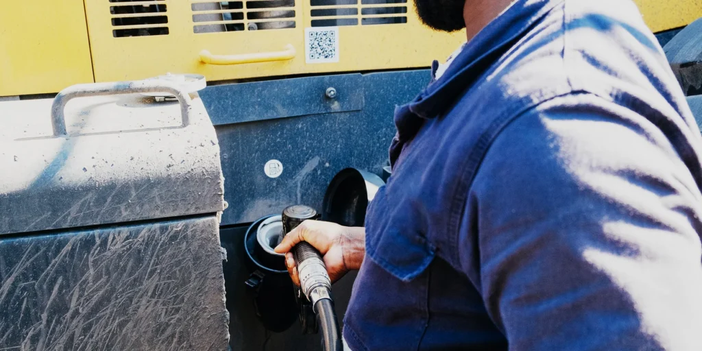 Technician refuelling heavy equipment with a diesel nozzle