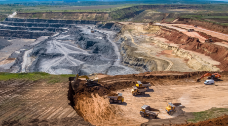 "Open-pit mining fleet of haul trucks and excavators operating across tiered benches — managed with SmartDSM™ mining fleet analytics